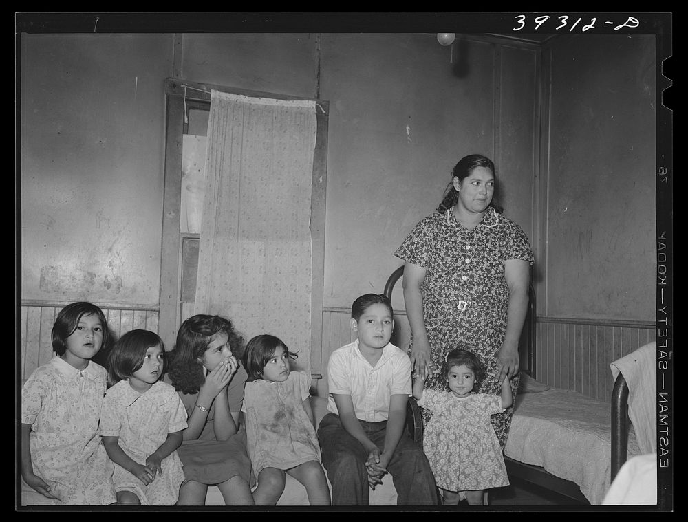 Mexican children with their mother sitting on bed in their home. San Diego, California by Russell Lee