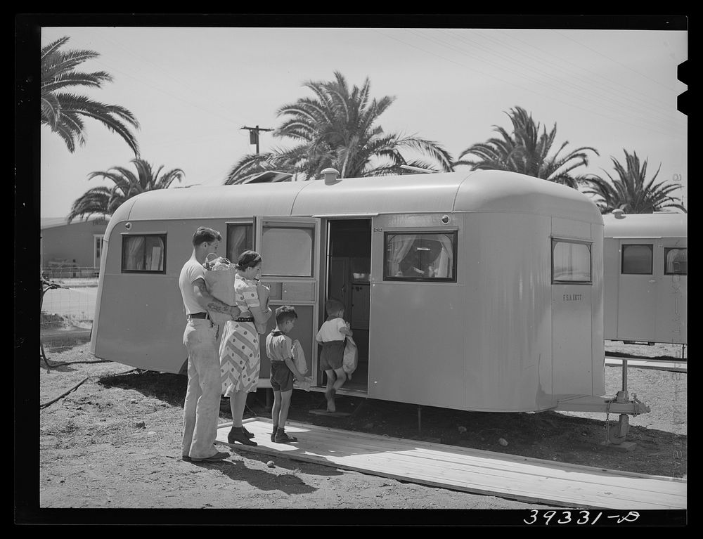Family moving into trailer at the FSA (Farm Security Administration) camp for defense workers. This family is from…