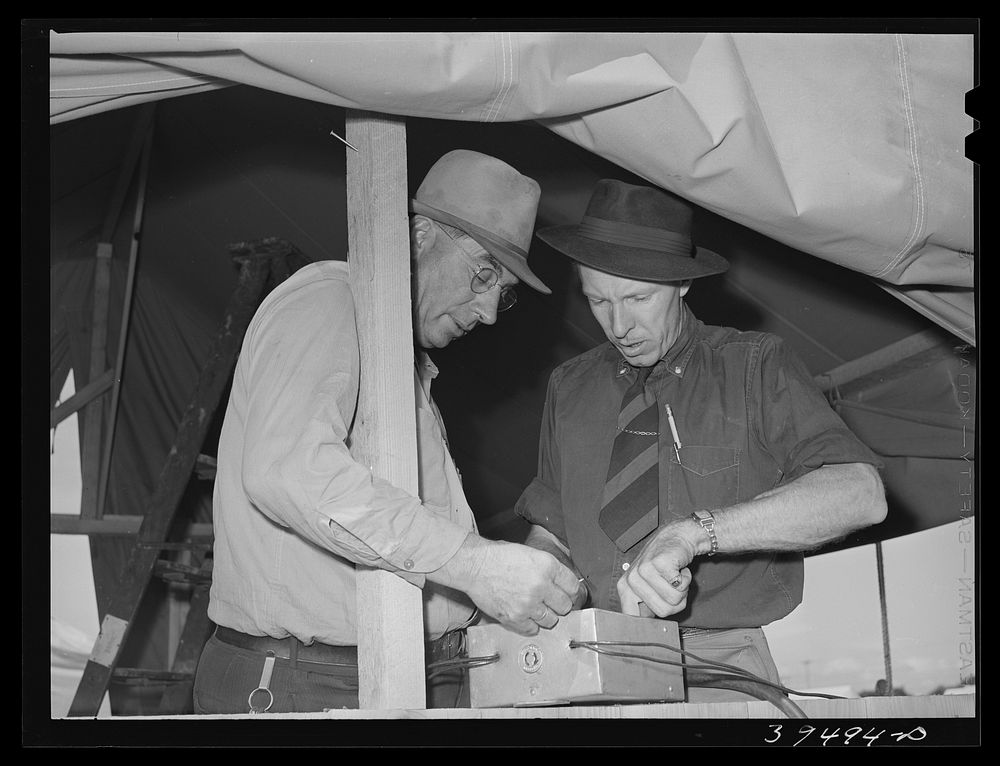 Camp manager, right, and engineer, left, check electrical connection. Mobil unit, FSA (Farm Security Administration) labor…