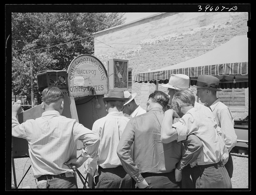 Men gathered around one of the carnival attractions which was in Vale, Oregon, for the Fourth of July celebration by Russell…