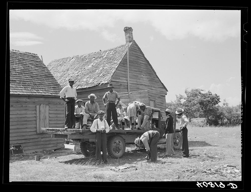 Part of a crew of thirty-five migrants who come up in this truck and who stay in the farmhouse in background. It is Sunday…