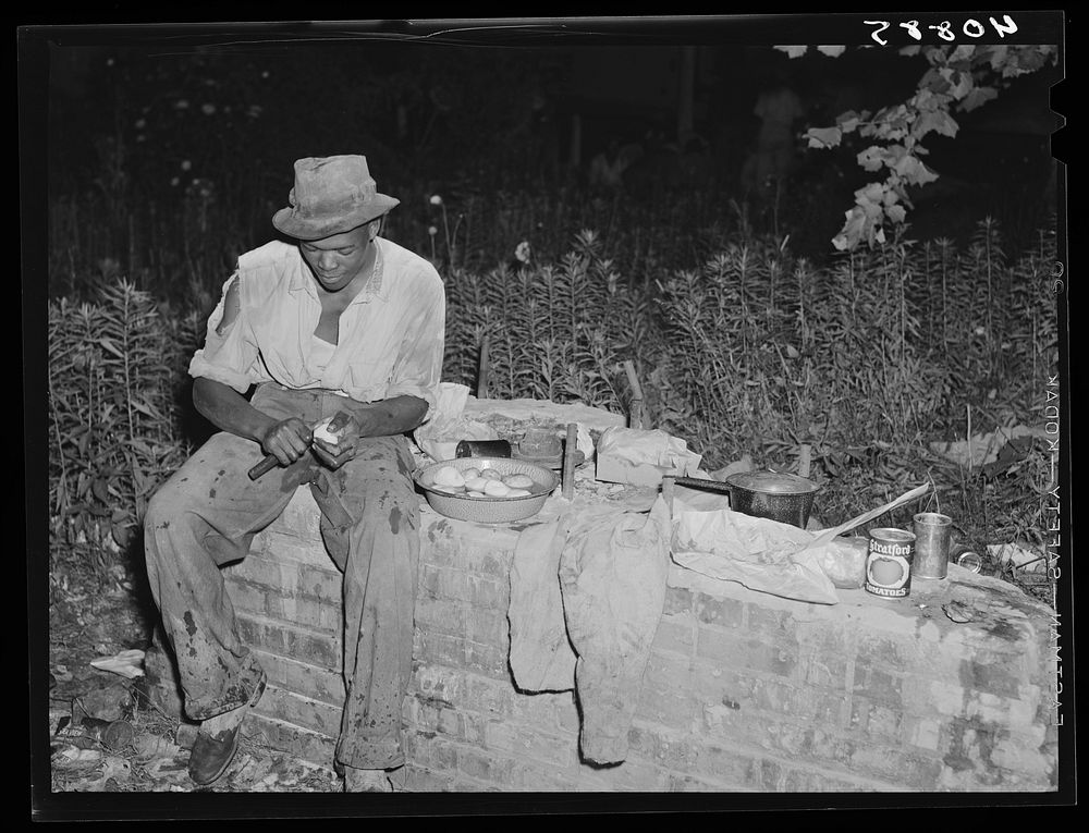 Migratory worker at Belcross, North Carolina, grading station preparing supper to be cooked over an open fire. Sourced from…