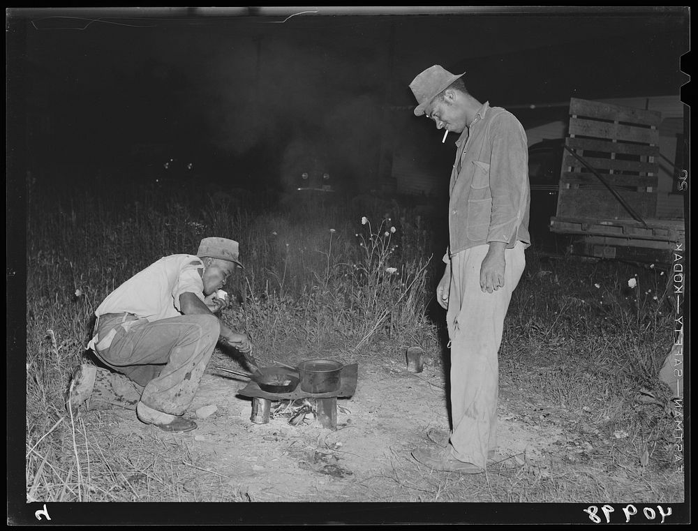 Mirgratory agricultural workers from the grading station at Belcross, North Carolina, cook their own supper of potatoes and…
