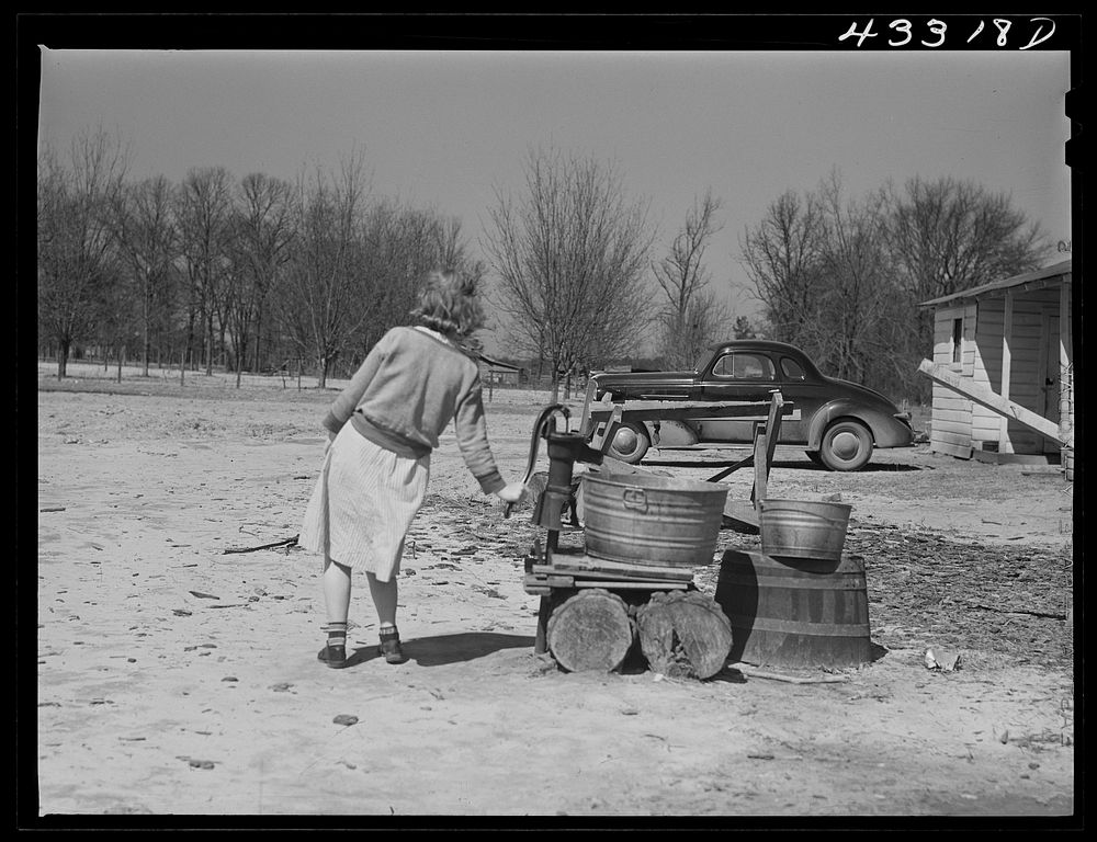 [Untitled photo, possibly related to: Woman fetching water. She lives with her family in lower part of the tobacco barn.…