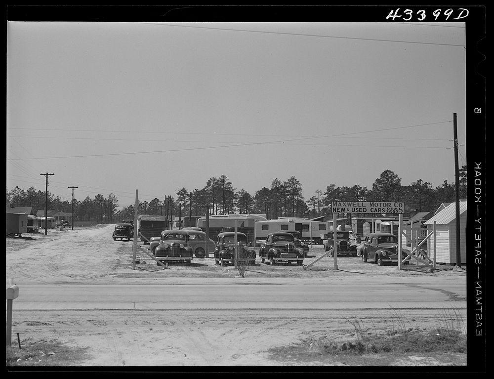 A used car lot adjacent to a trailer settlement of workers from Fort Bragg. Near Fayetteville, North Carolina. Sourced from…