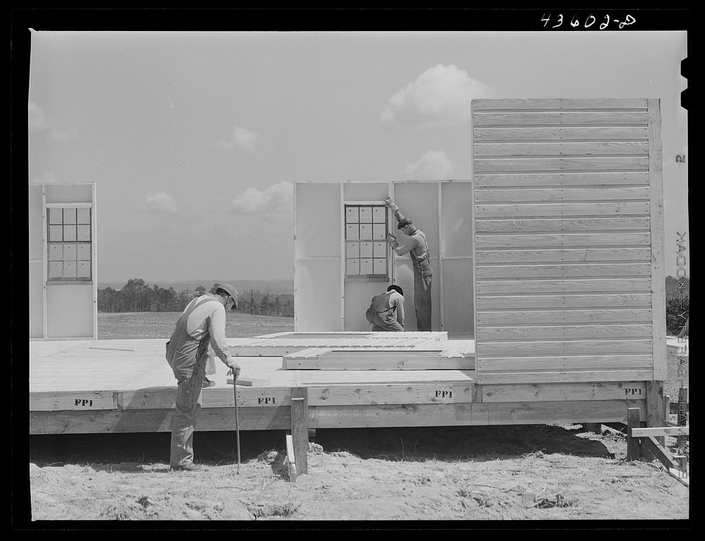 Building porch on prefabricated houses to be used to house some of the farmers that had to move out of Camp Croft area.…