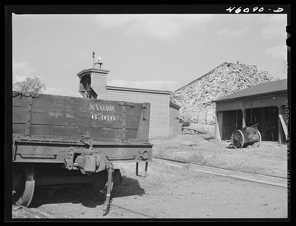 Railroad car and wood pile at the Missisquoi Corporation paper mill in Sheldon Springs, Vermont. Sourced from the Library of…