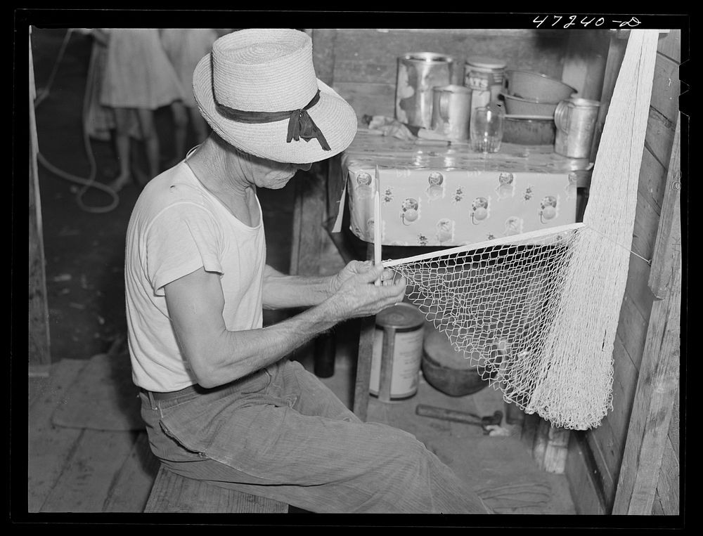 French village, a small settlement on Saint Thomas Island, Virgin Islands. French fisherman repairing his net at home in the…