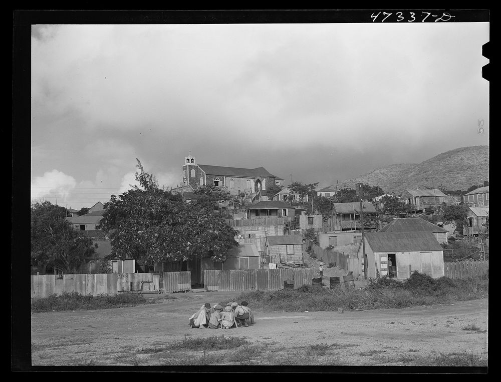 French village, a small settlement on Saint Thomas Island, Virgin Islands. Children playing marbles. The Catholic church on…