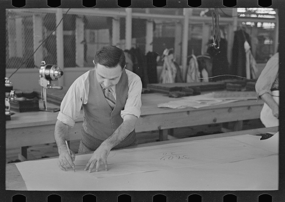 Louis Gushen, chief cutter in the cooperative garment factory at Jersey Homesteads, is cutting the pattern for a woman's…