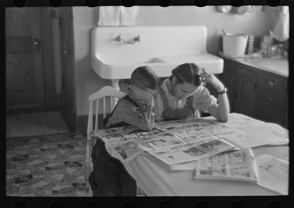Children reading Sunday papers, Rustan brothers' farm near Dickens, Iowa. Note convenience of running water in background.…
