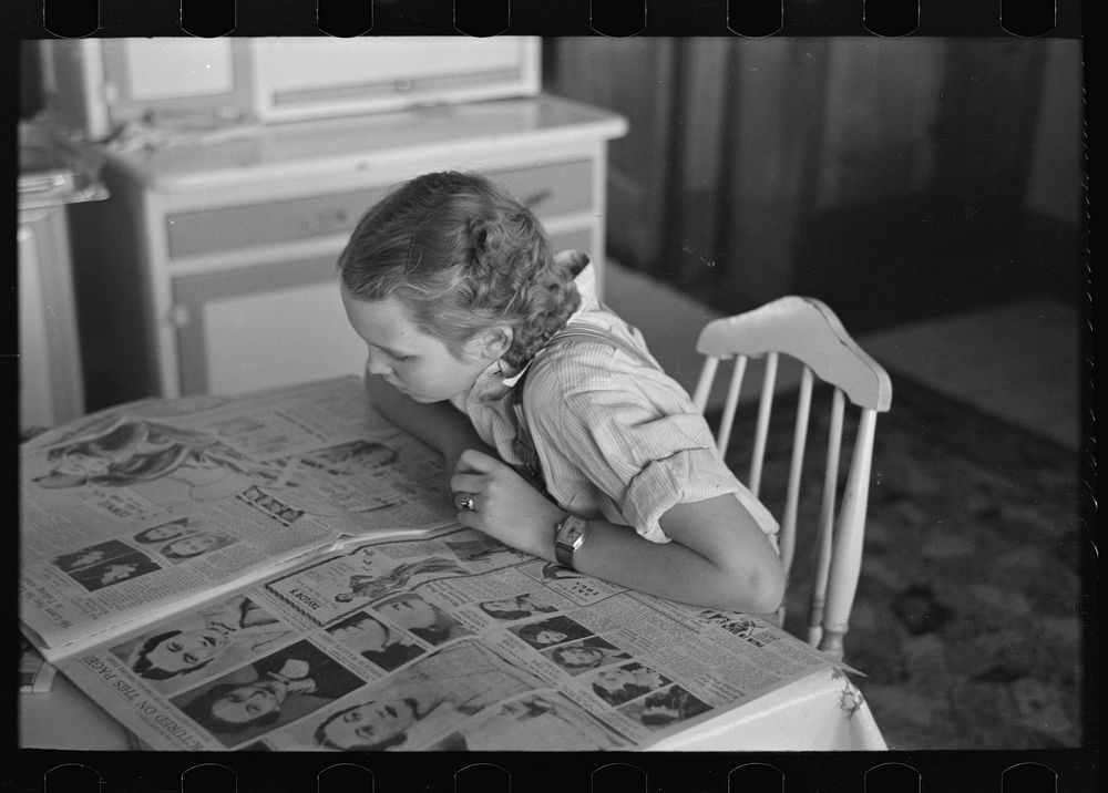 [Untitled photo, possibly related to: Rustan's daughter reading a Sunday paper. Rustan brothers' farm near Dickens, Iowa] by…