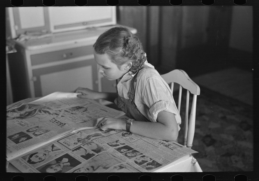 Rustan's daughter reading a Sunday paper. Rustan brothers' farm near Dickens, Iowa by Russell Lee