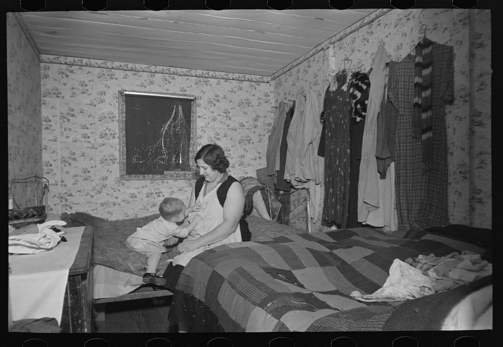 Mother and child in crowded bedroom of home of L.H. Nissen, hired man. He is married, has seven children, one grandchild…