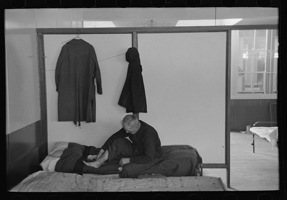 [Untitled photo, possibly related to: Man examining ankle, homeless men's bureau, Sioux City, Iowa] by Russell Lee