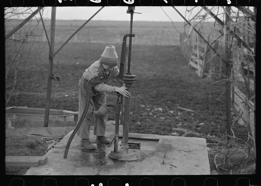 Late afternoon. One of Tip Estes' sons disconnects pipe from the windmill pump. Fowler, Indiana by Russell Lee