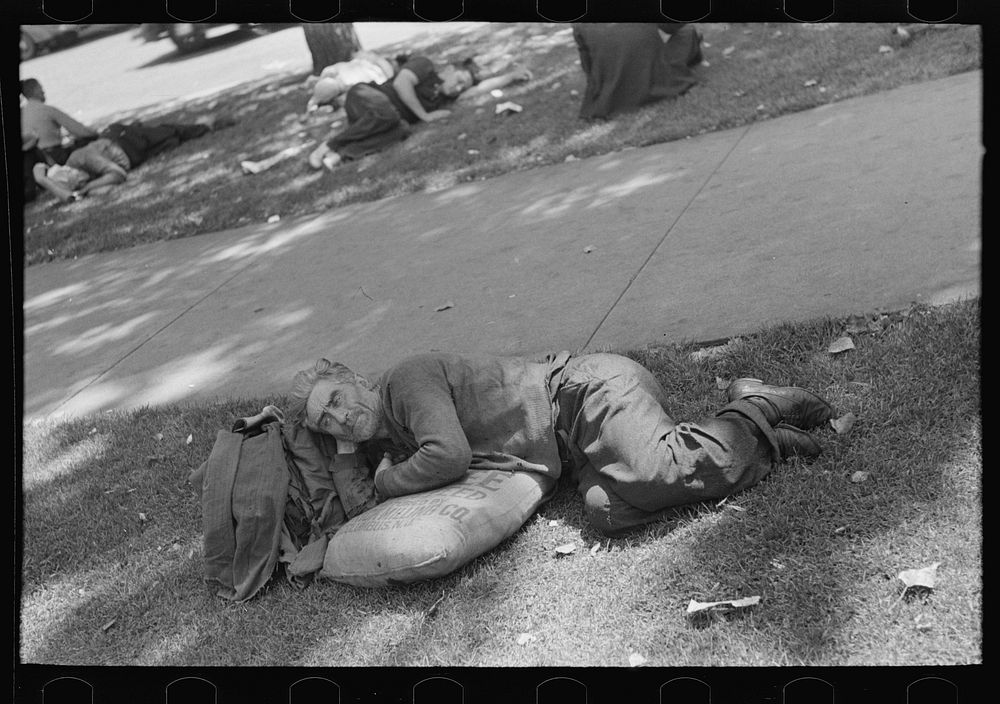 Man resting in park on sack of scratch seed, Minneapolis, Minnesota by Russell Lee