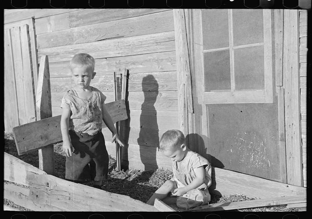 Sons of Floyd Peaches playing around their home near Williston, North Dakota by Russell Lee