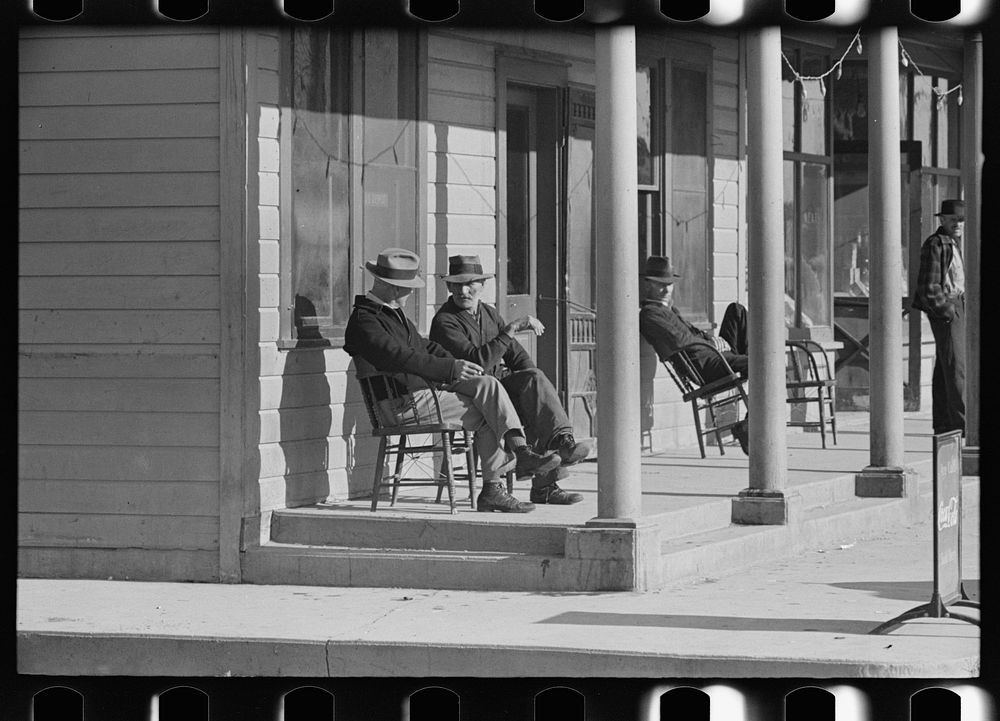 Men sitting in front of hotel in the early morning, Little Fork, Minnesota by Russell Lee