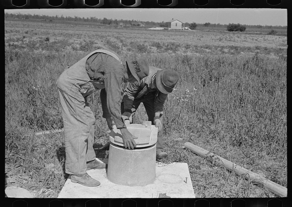 [Untitled photo, possibly related to: Southeast Missouri Farms Project. Fitting vent stack and seat cover to sanitary base…