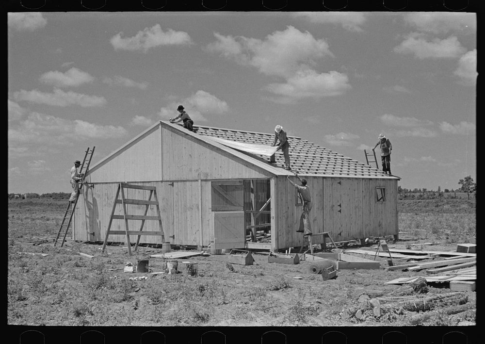 Barn erection. Placing corrugated metal roofing. Southeast Missouri Farms Project by Russell Lee