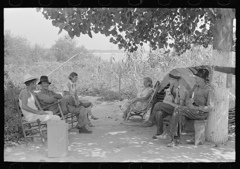 Residents of "Tin Town" sitting in the shade, near Caruthersville, Missouri by Russell Lee