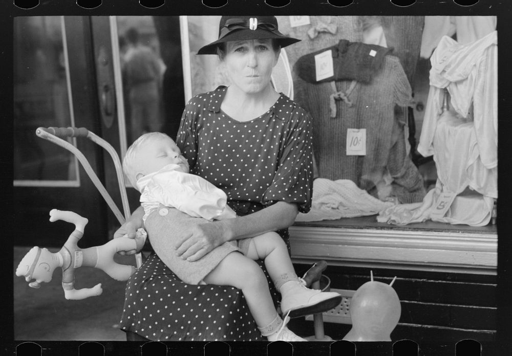 Woman with child in front of store during National Rice Festival, Crowley, Louisiana by Russell Lee