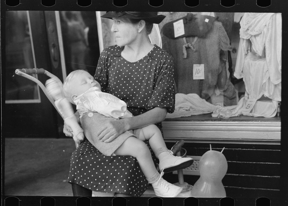 [Untitled photo, possibly related to: Woman with child in front of store during National Rice Festival, Crowley, Louisiana]…