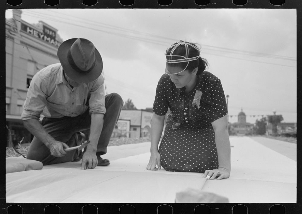 [Untitled photo, possibly related to: Tacking down canvas on queen's platform before opening of National Rice Festival…