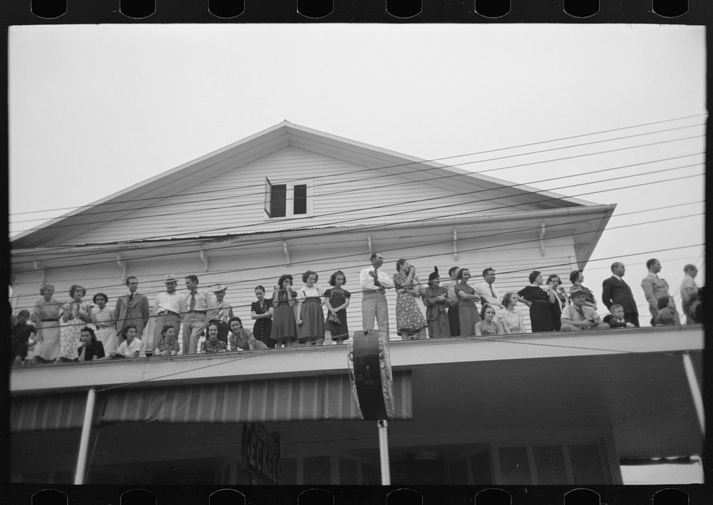 Group of people on top of roof watching parade, National Rice Festival, Crowley, Louisiana by Russell Lee