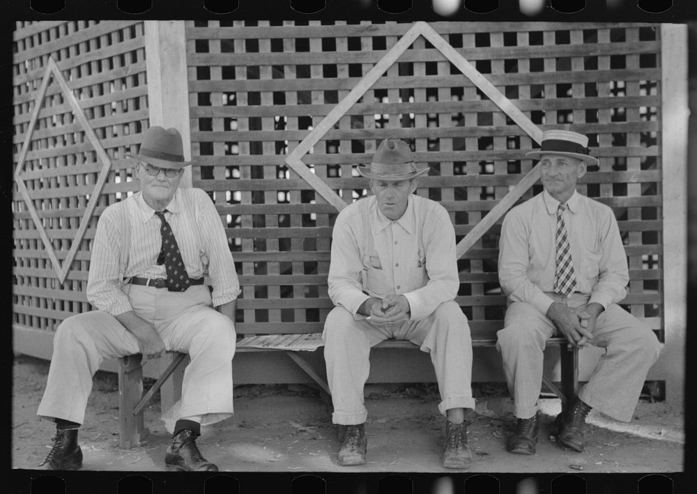 Men sitting on bench in front of bandstand in courthouse square, New Iberia, Louisiana by Russell Lee