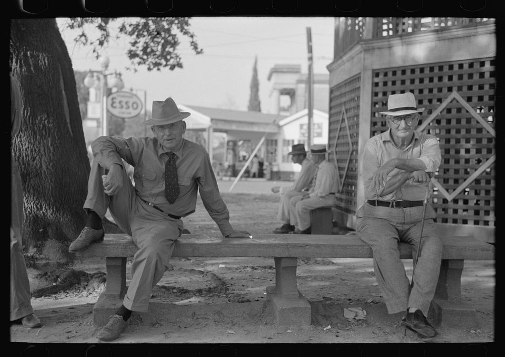 Men sitting on bench in front of bandstand in courthouse square, New Iberia, Louisiana by Russell Lee