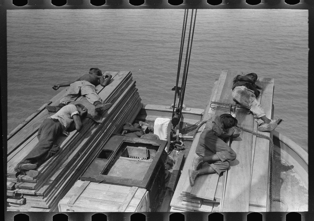  stevedores sleeping on pile of lumber on bow of packet boat on Mississippi River below New Orleans, "El Rito" by Russell Lee