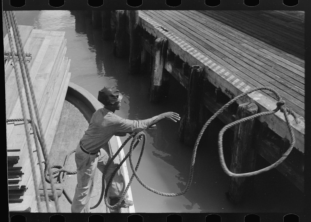 A man deck hand throwing line in docking operations, Burrwood, Louisiana by Russell Lee