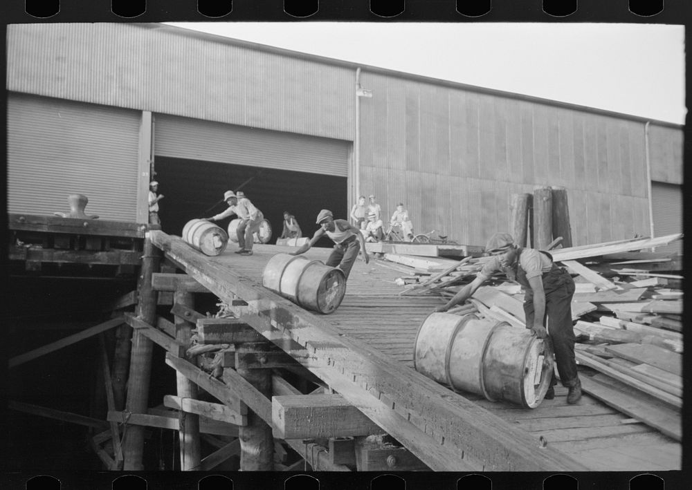  stevedores "snaking" drums down ramp to boat, New Orleans, Louisiana by Russell Lee