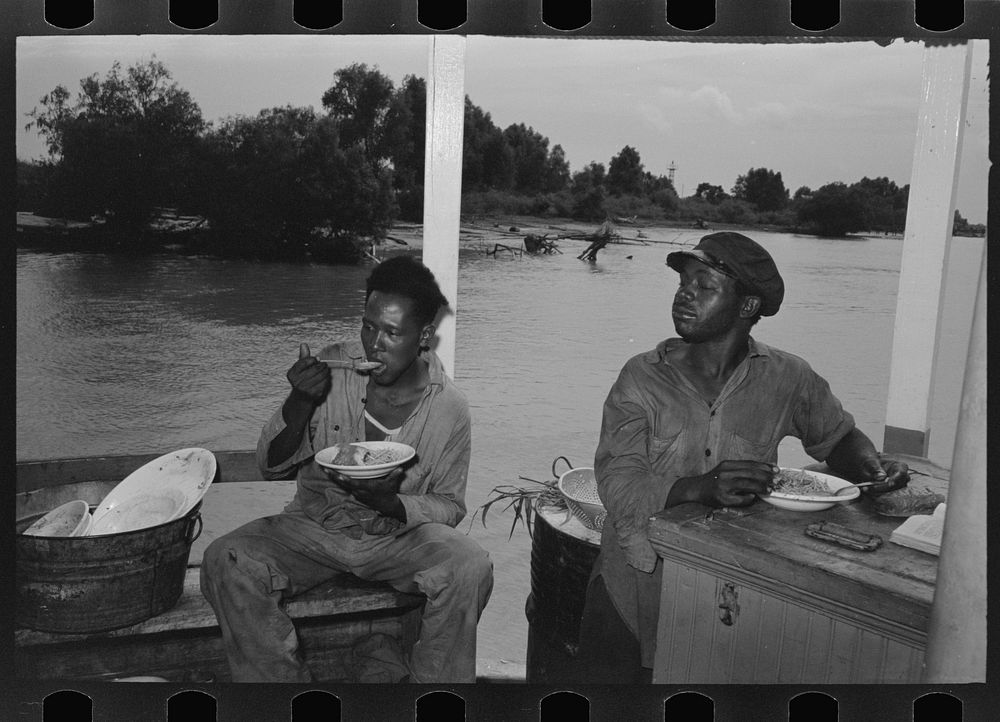  stevedores eating on stern of boat. Food supplied to crew consists almost entirely of carbohydrates with some of the…