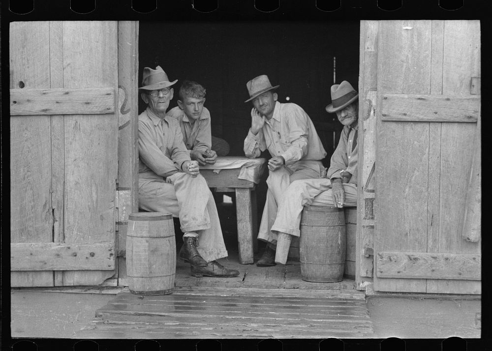 Group of men in a shack on the levee near Norco, Louisiana. They were taking refuge from the rain by Russell Lee