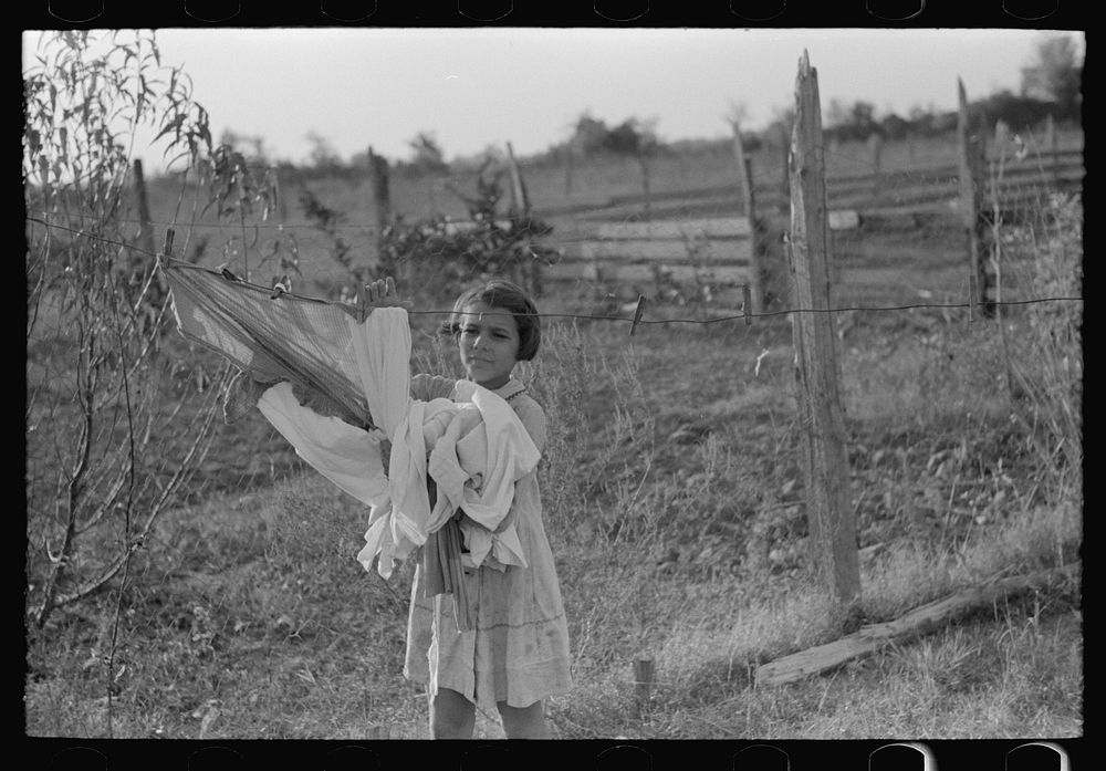 Daughter of Cajun cane farmer removing clothes from line near New Iberia, Louisiana by Russell Lee