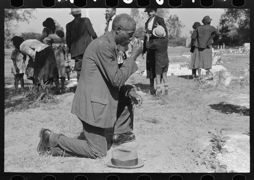 Man crossing himself and praying over grave of relative in cemetery, All Saints' Day, New Roads, Louisiana by Russell Lee