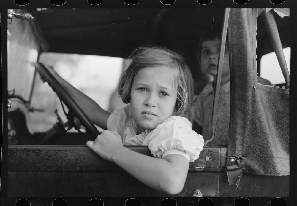 [Untitled photo, possibly related to: Child of farmer sitting in automobile waiting for father to come out of general store…