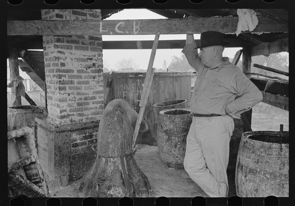 [Untitled photo, possibly related to: Owner atop his turpentine still. Goosneck runs from the still to the condenser coils…