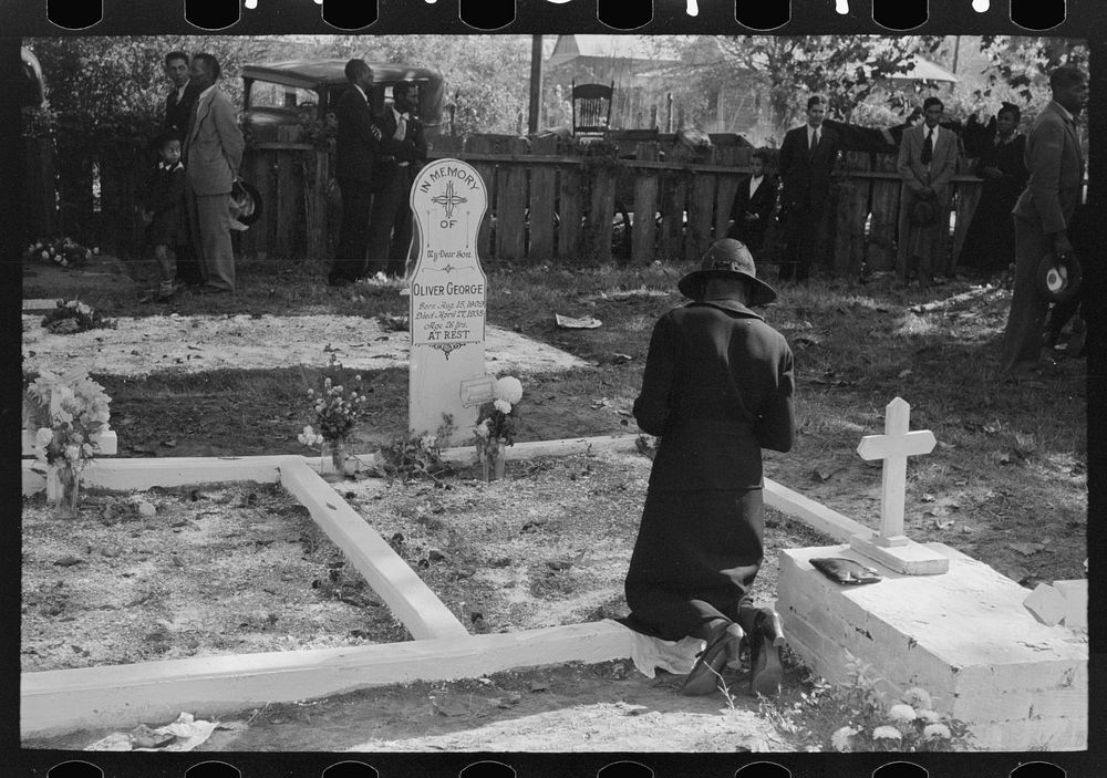 Women praying at grave of son in cemetery at New Roads, Louisiana on All Saints' Day by Russell Lee