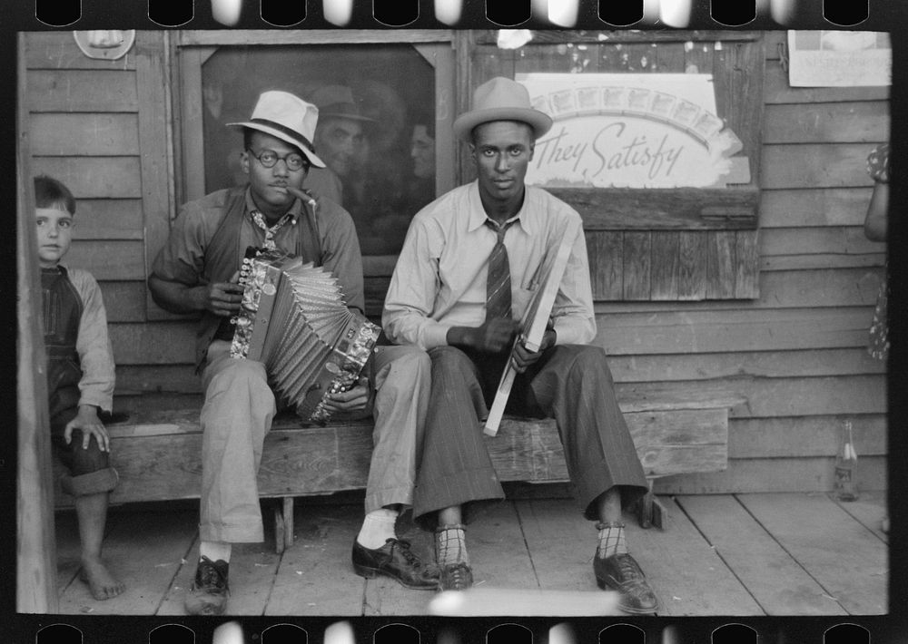 Musicians playing accordion and washboard in front of store, near New Iberia, Louisiana by Russell Lee