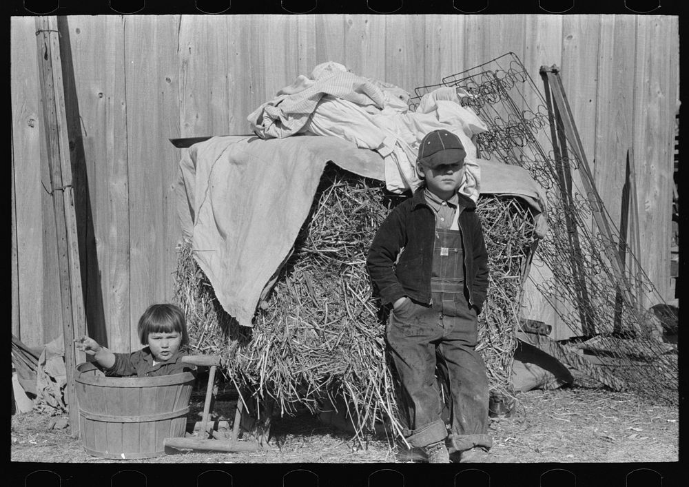 Children in front of household goods at side of house. These people came from a western parish and brought all their…