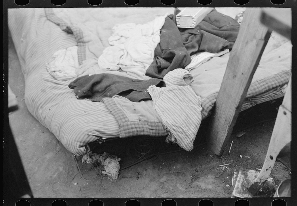 Bed of white migrant worker consisting of mattress on the ground near Harlingen, Texas by Russell Lee