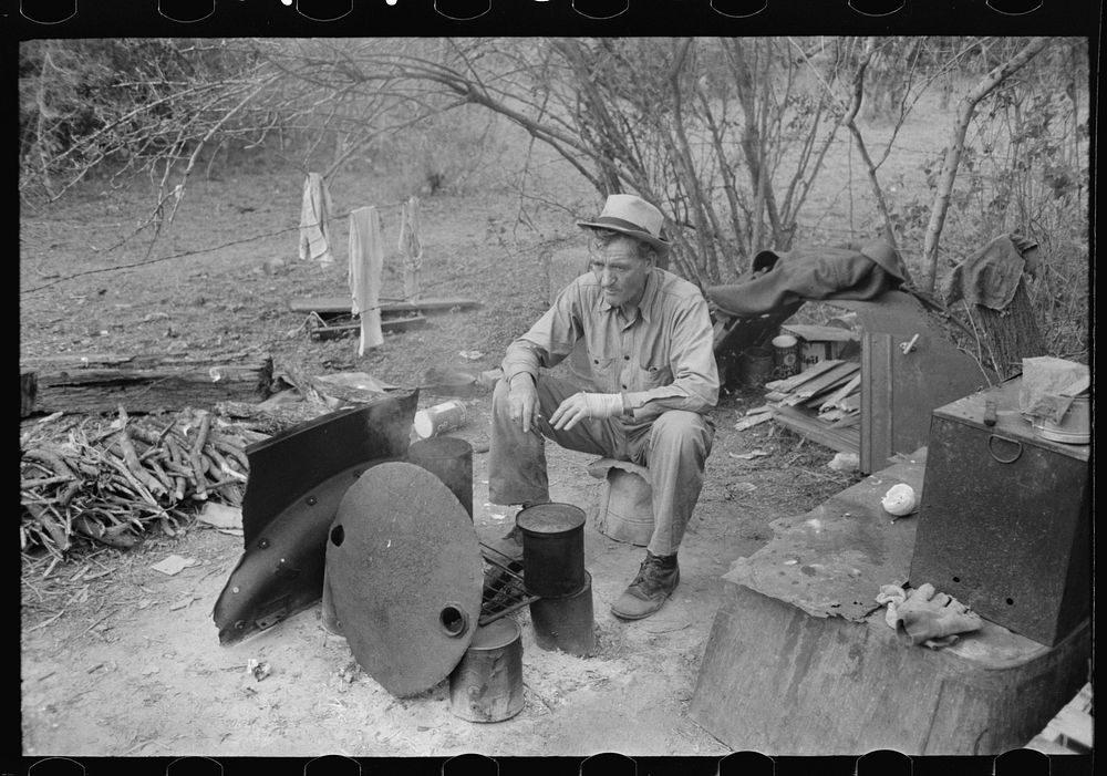White migrant worker sitting in front of fire. He lived with two other white men migrant workers. He was a Texan. Harlingen…