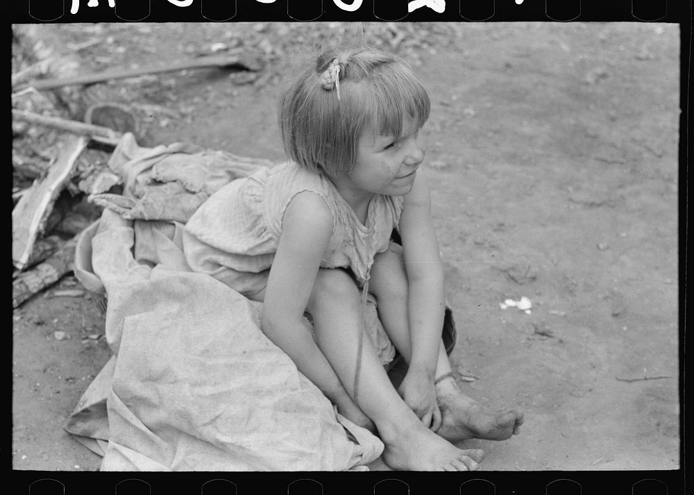 Child of white migrant worker sitting on cotton pickers' sacks near Harlingen, Texas by Russell Lee