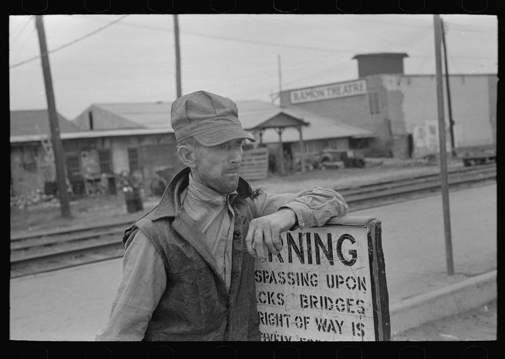 Day laborer resting on sign near railroad platform, Raymondville, Texas by Russell Lee