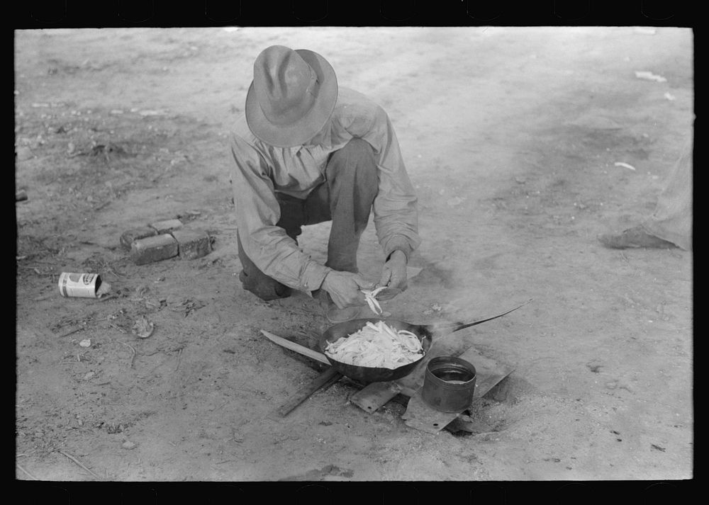 Migrant worker cooking meal over campfire, Edinburg, Texas by Russell Lee