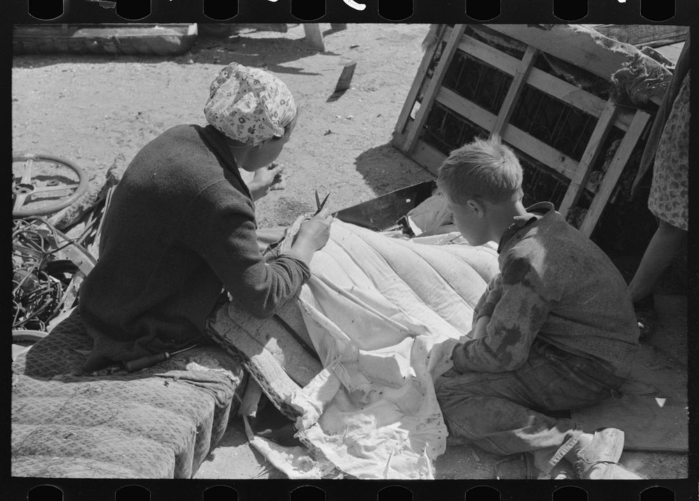 [Untitled photo, possibly related to: Wife of migrant auto wrecker sewing seat cushion of wrecked auto, Corpus Christi…